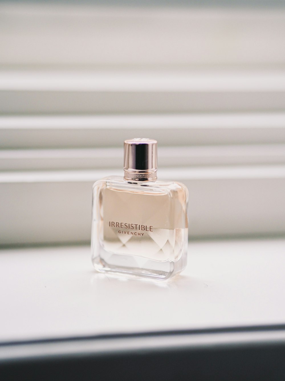 clear glass perfume bottle on white surface