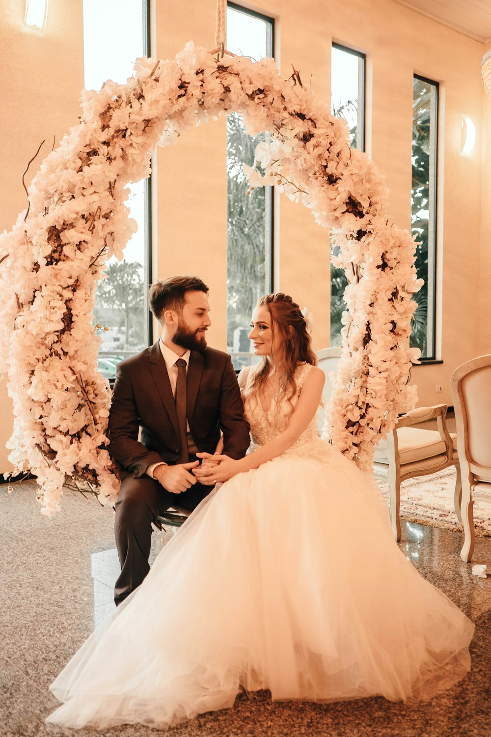 man in black suit and woman in white wedding dress sitting on chair