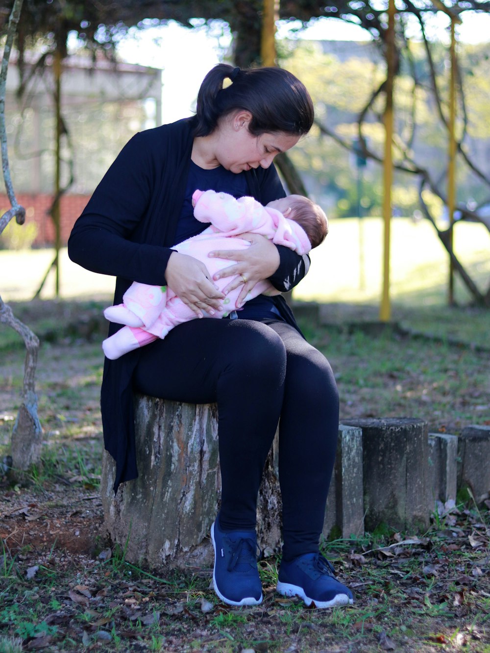 woman in black long sleeve shirt carrying baby in pink jacket