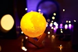 A close-up photo of a customized 3D printed moon lamp glowing softly on a decorated table.