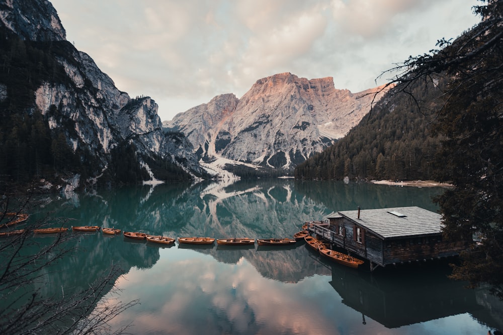 brown wooden house on lake near rocky mountain during daytime