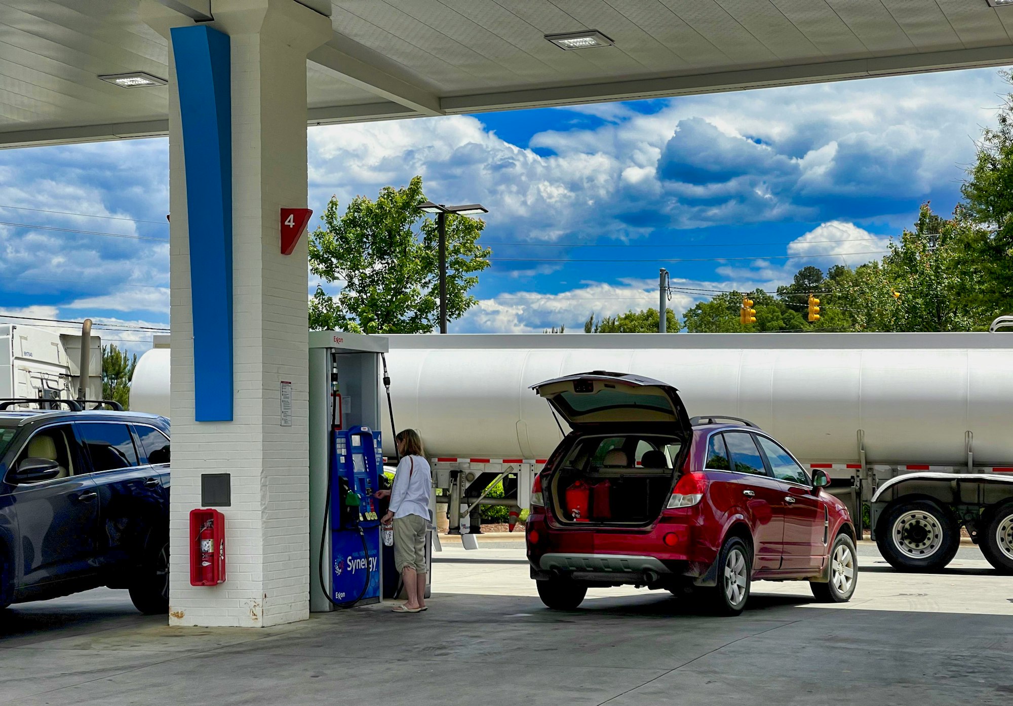 Woman pumps gas while an oil truck brings gas to refill tanks at a gas station in Pittsboro, North Carolina.