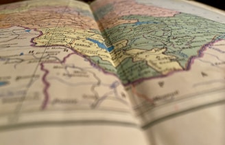 A close-up view of a colorful, detailed map, slightly out of focus in the foreground, with visible borders, names of countries, and geographical features.