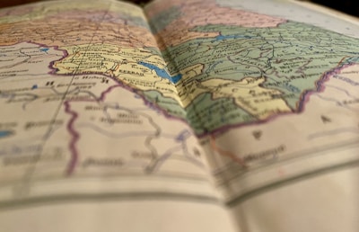 A close-up view of a colorful, detailed map, slightly out of focus in the foreground, with visible borders, names of countries, and geographical features.