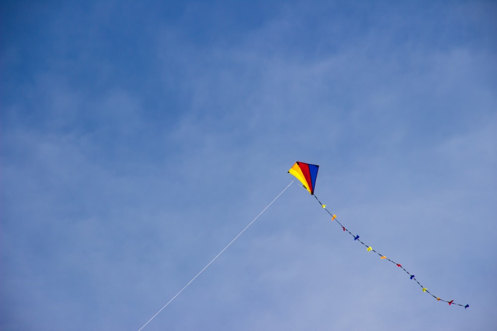 Cerf-volant jaune et bleu volant sous un ciel bleu pendant la journée