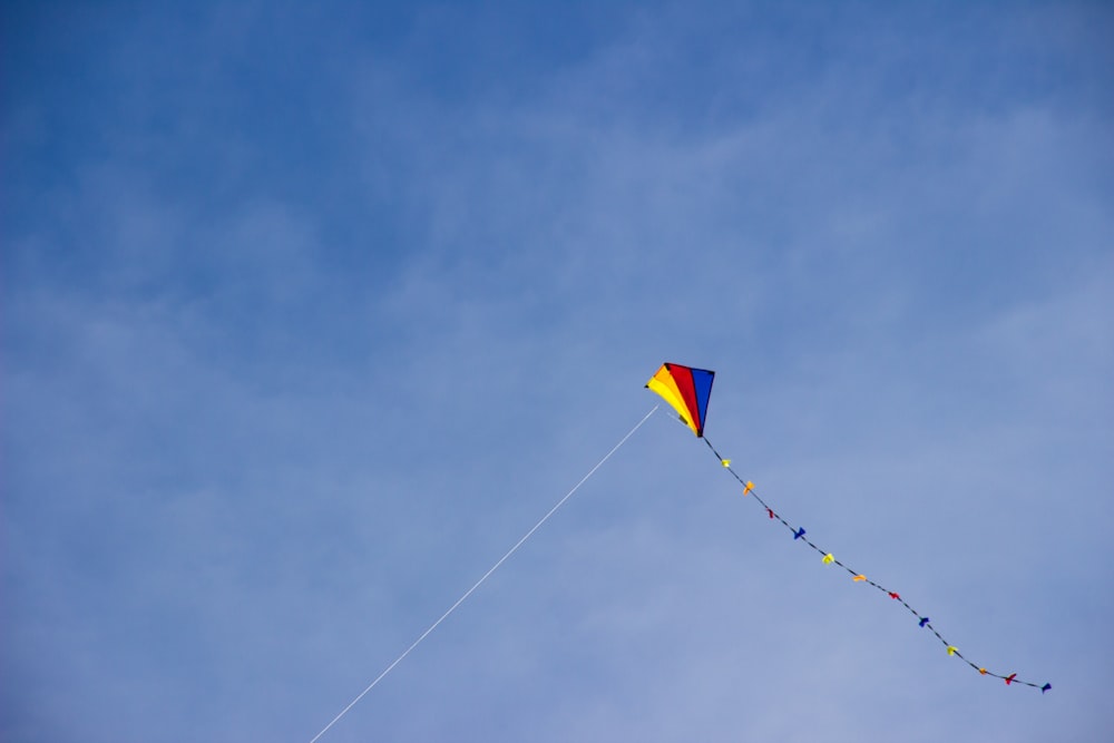 yellow and blue kite flying under blue sky during daytime