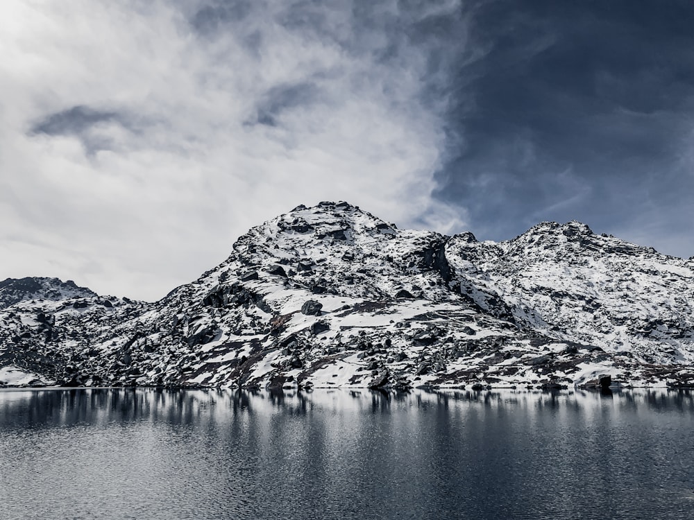 snow covered mountain near body of water during daytime