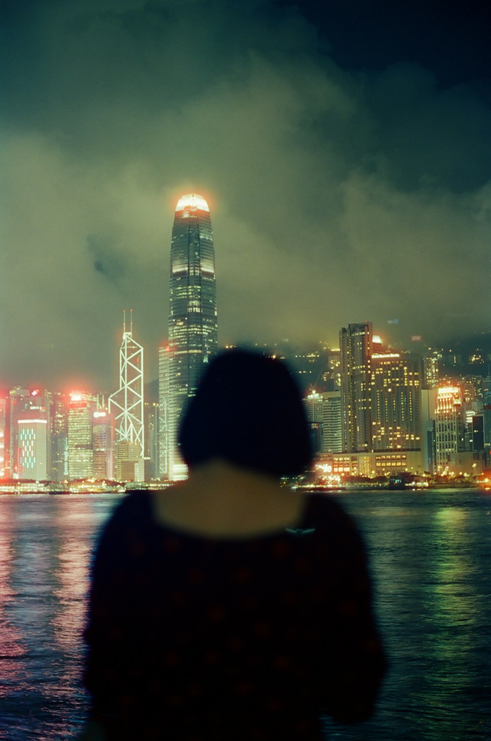 man in black jacket standing near body of water during night time