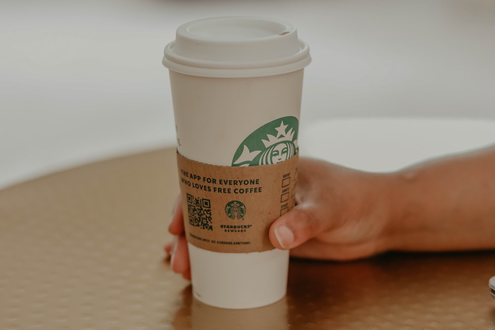 person holding white and green plastic cup