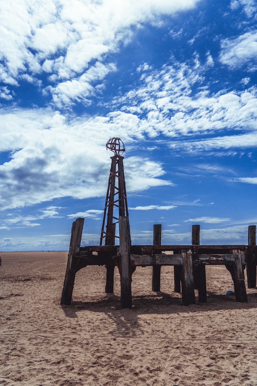 brown wooden fence on brown sand under blue sky and white clouds during daytime