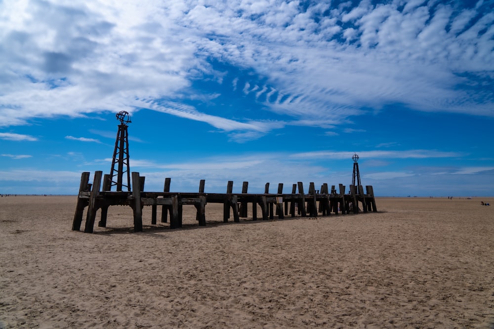 brown wooden fence on brown sand under blue sky during daytime