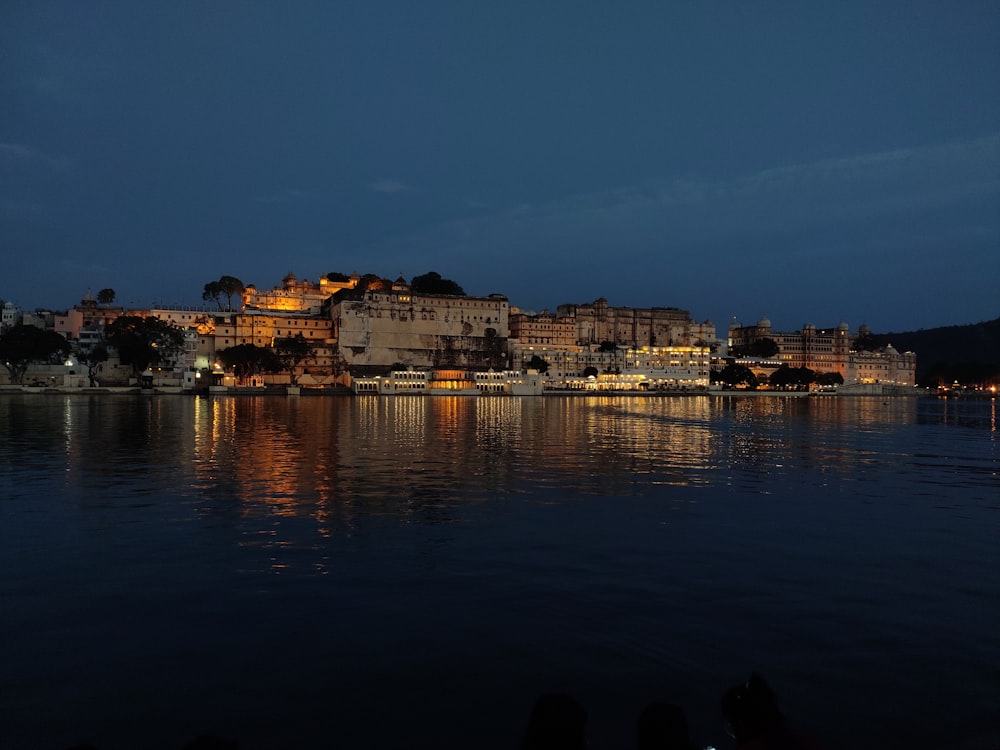 city skyline across body of water during night time