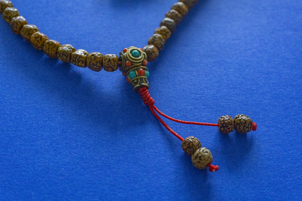 a close up of a beaded necklace on a blue surface