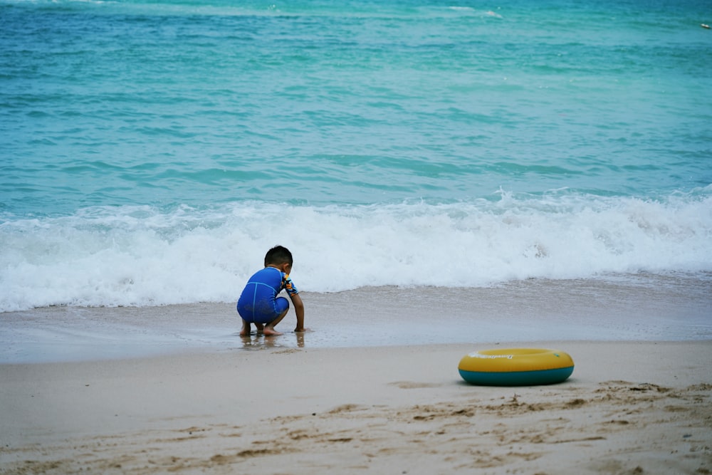 Mujer en bikini azul y blanco cargando tabla de surf azul en la playa durante el día