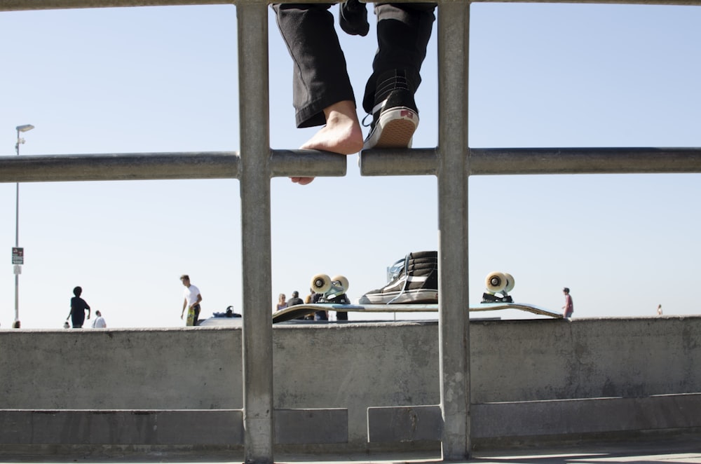 woman in black tank top and black leggings climbing on gray metal bar during daytime