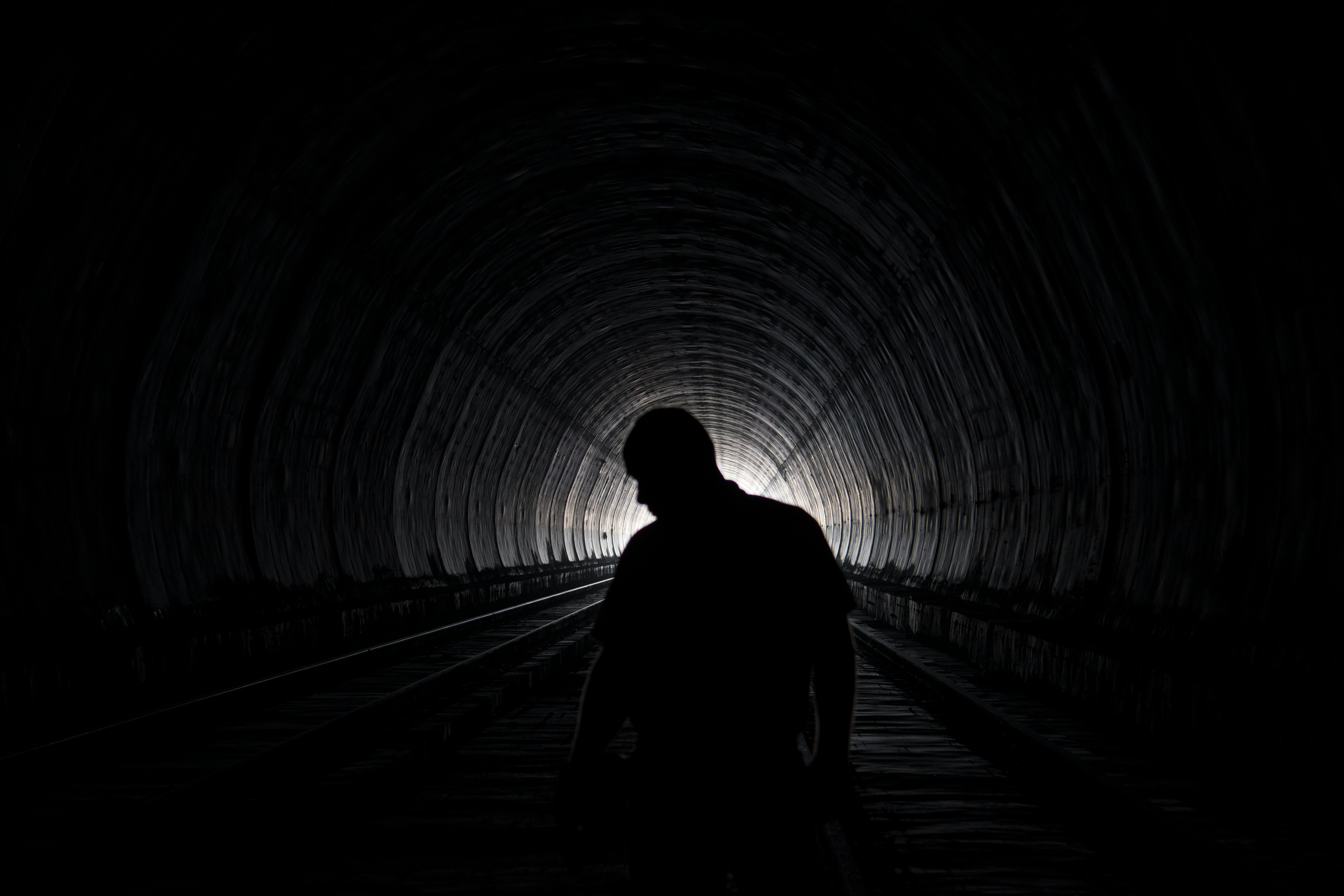 silhouette of person walking on tunnel during daytime