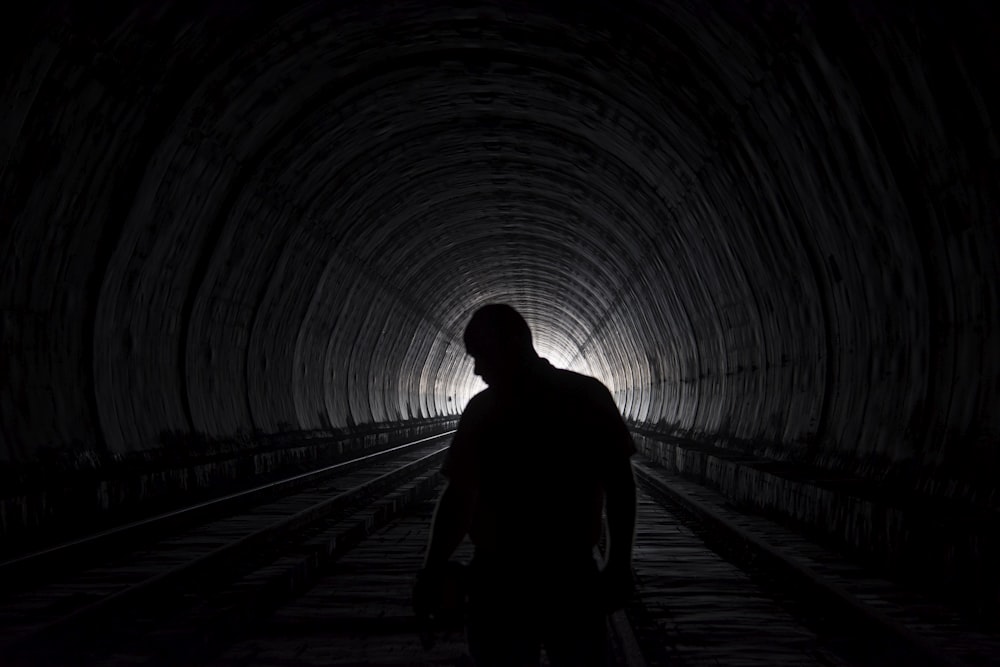 silhouette of person walking on tunnel during daytime