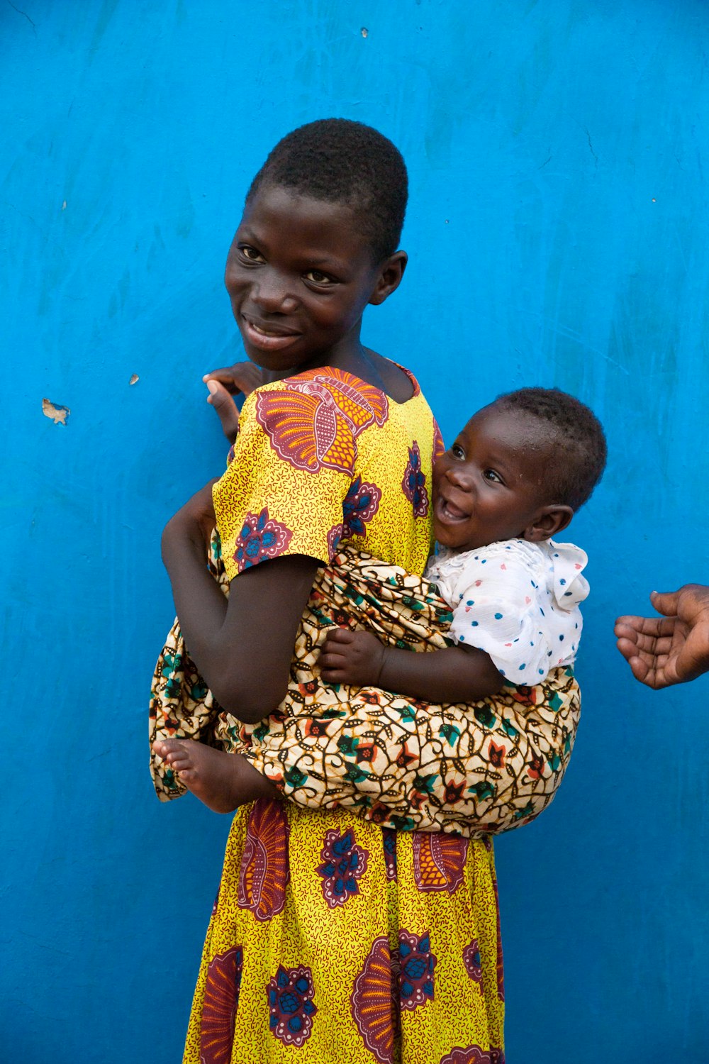 a woman holding a child in front of a blue wall