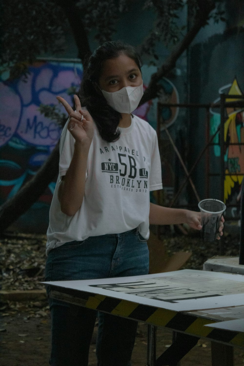 woman in white t-shirt and blue denim jeans wearing white face mask