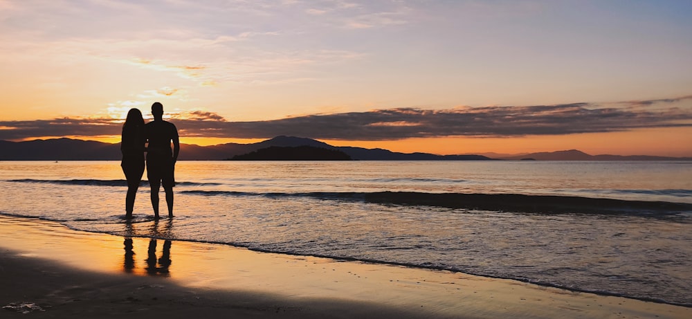 silhouette of mountain near body of water during sunset