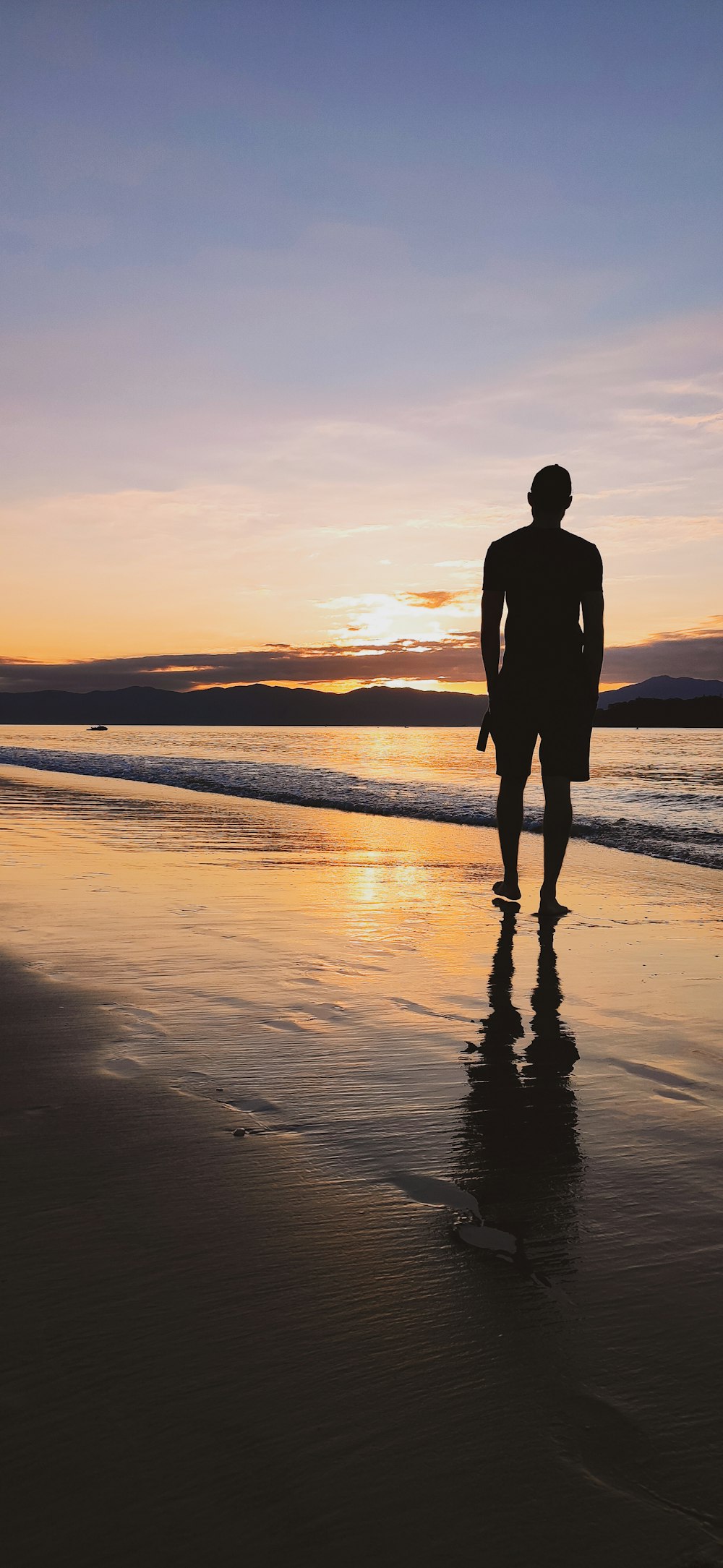 silhouette of man standing on beach during sunset