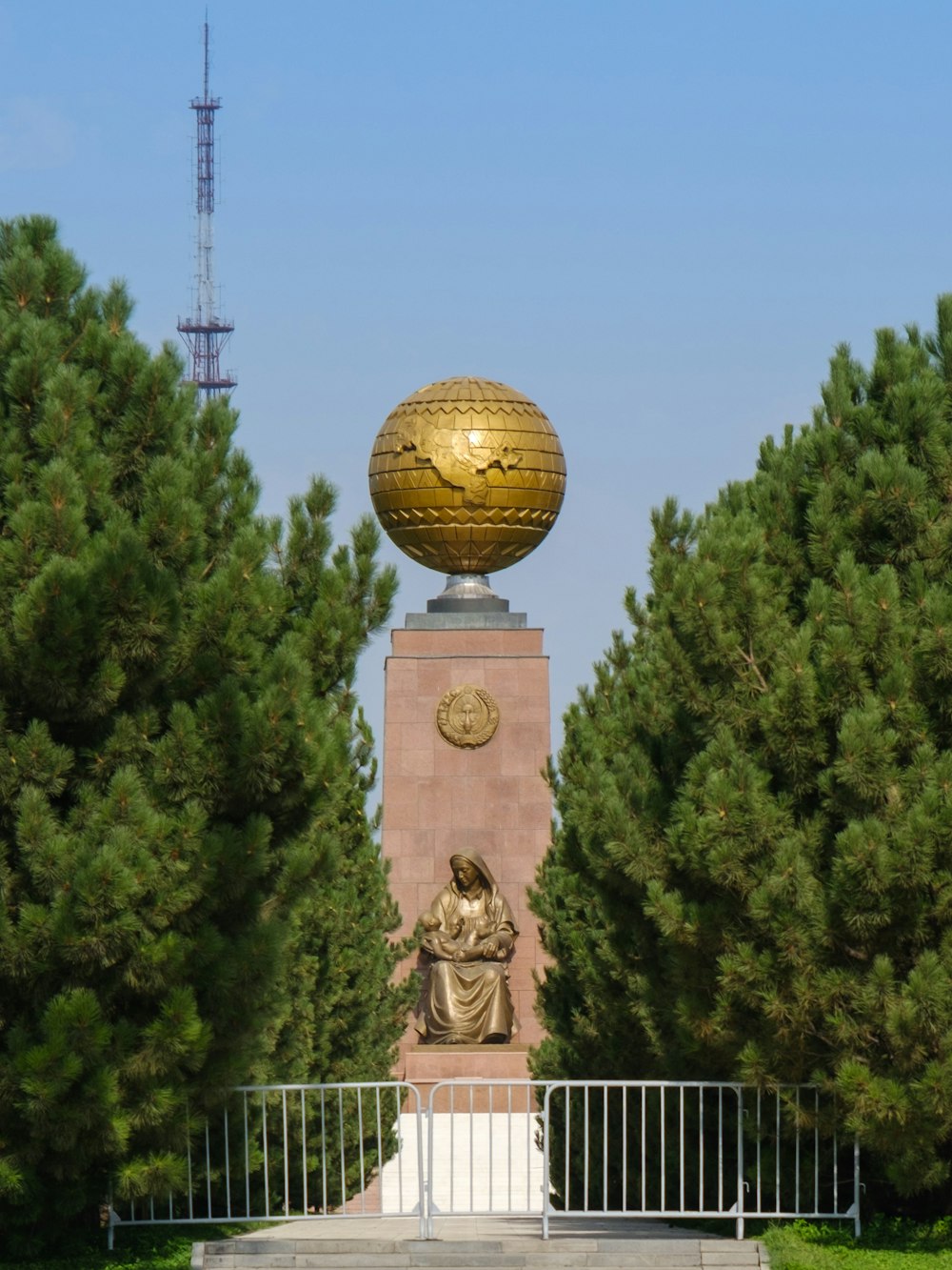 gold ball statue near green trees during daytime