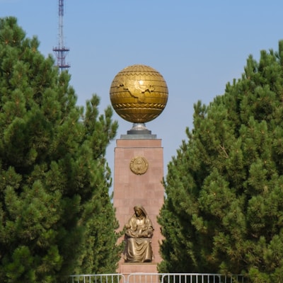 gold ball statue near green trees during daytime