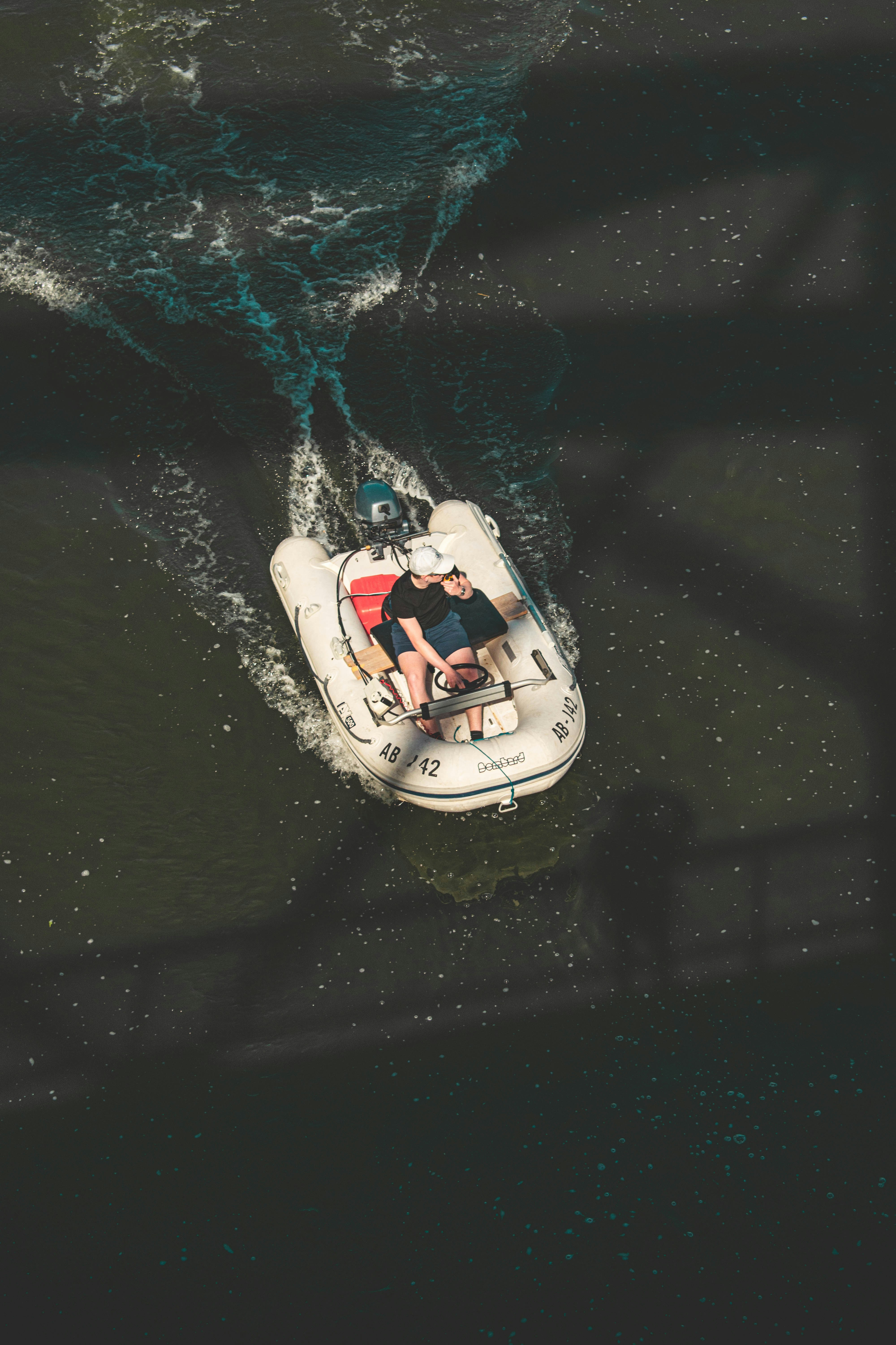 man in blue shirt riding white and red boat on water during daytime