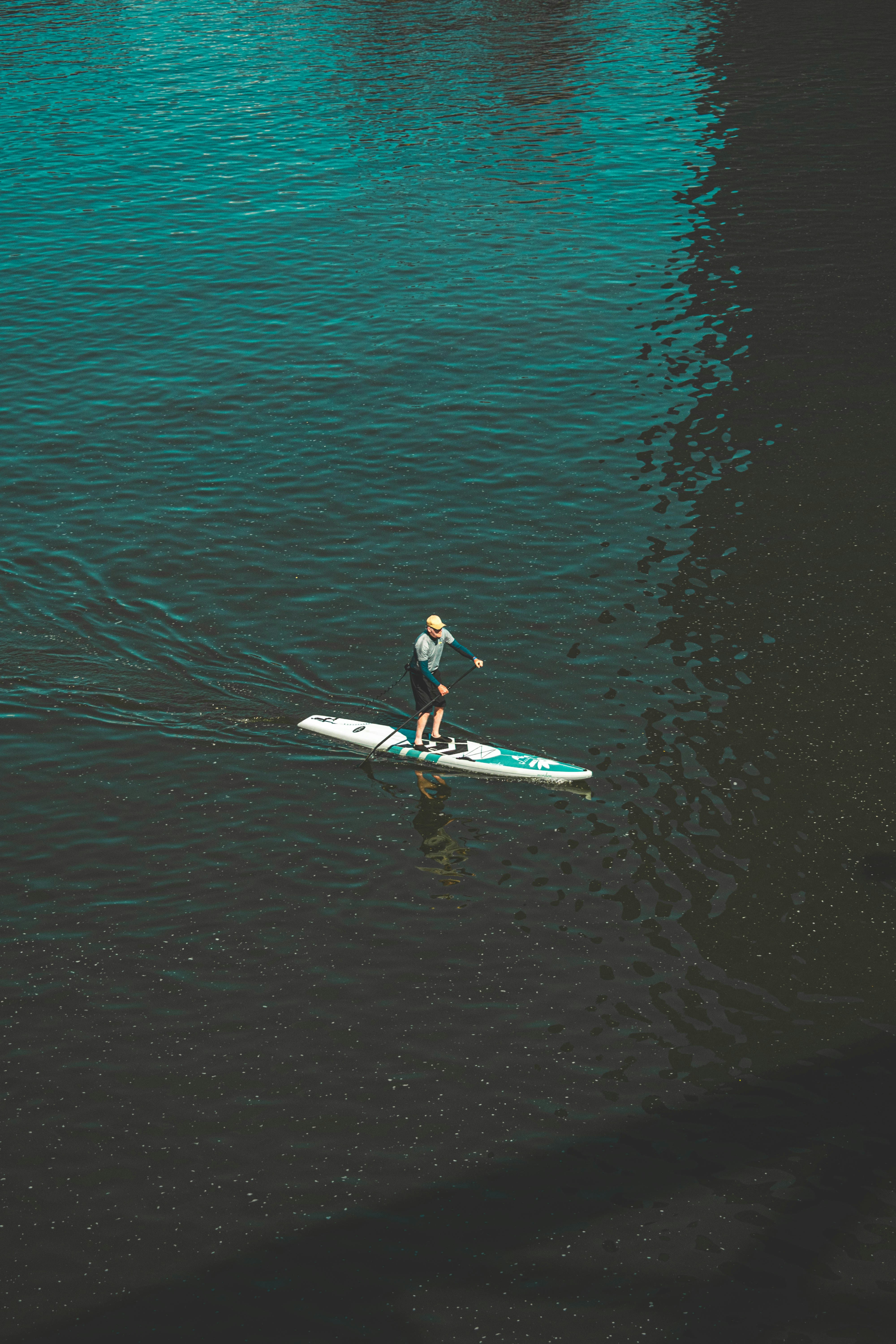 man in black wet suit riding white surfboard on body of water during daytime