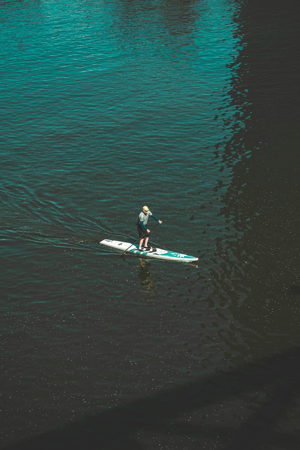 man in black wet suit riding white surfboard on body of water during daytime
