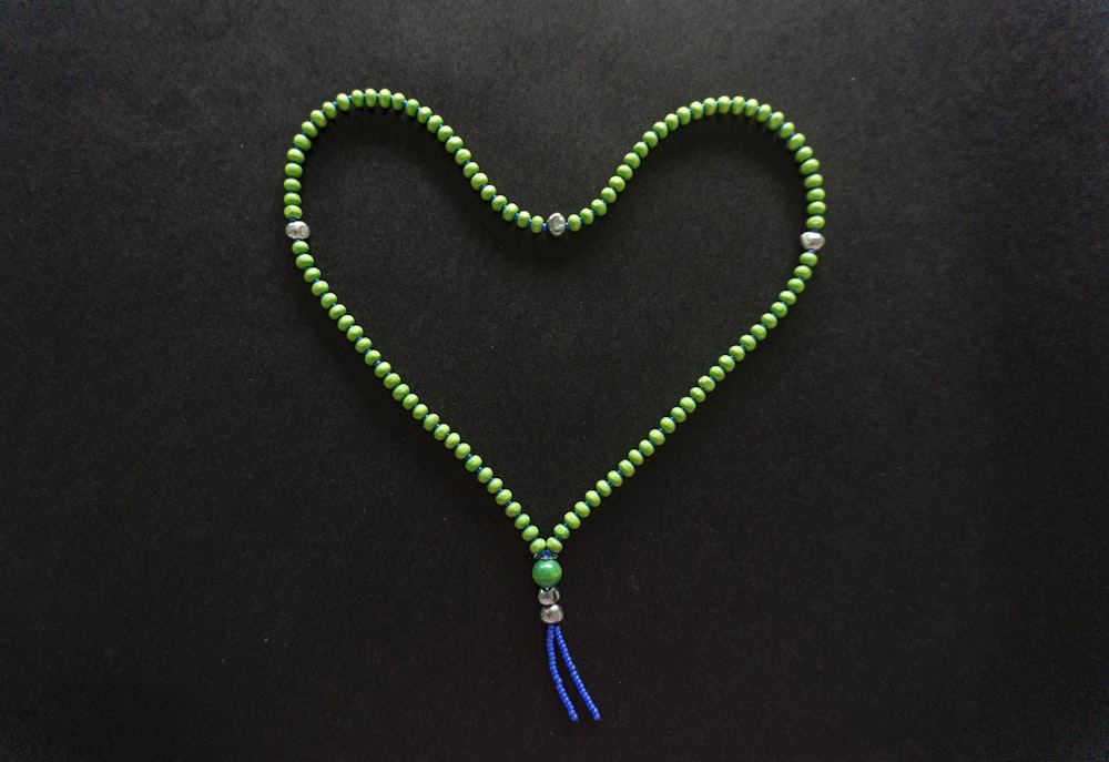 green beaded necklace on black textile