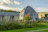 Wide shot of a minimalist wooden dome home set in a serene natural landscape.