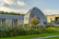Wide shot of a minimalist wooden dome home set in a serene natural landscape.