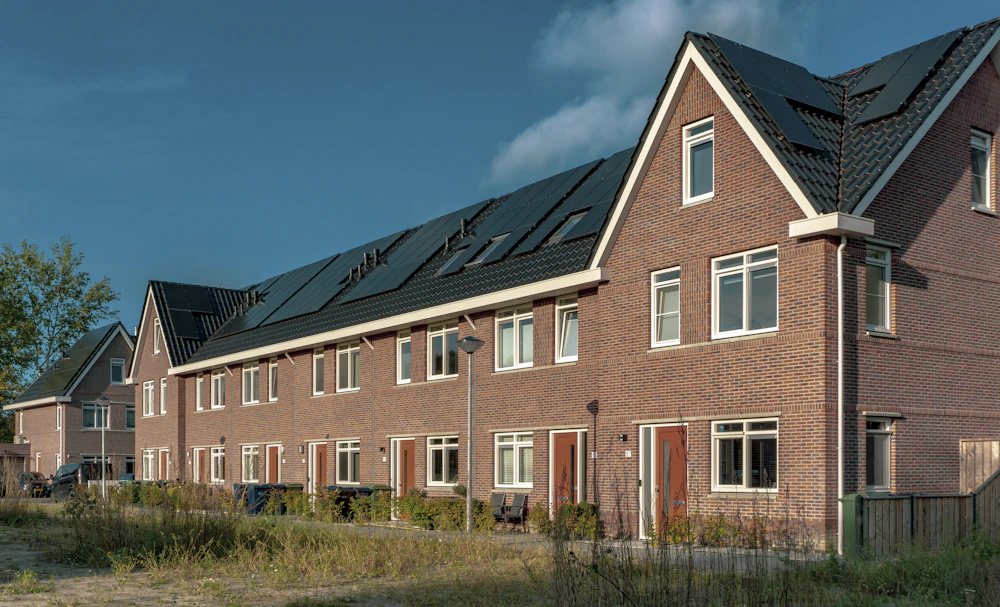 Rij Nederlandse bakstenen woningen met zonnepanelen op het dak als voorbeeld van een verduurzaamde woning
