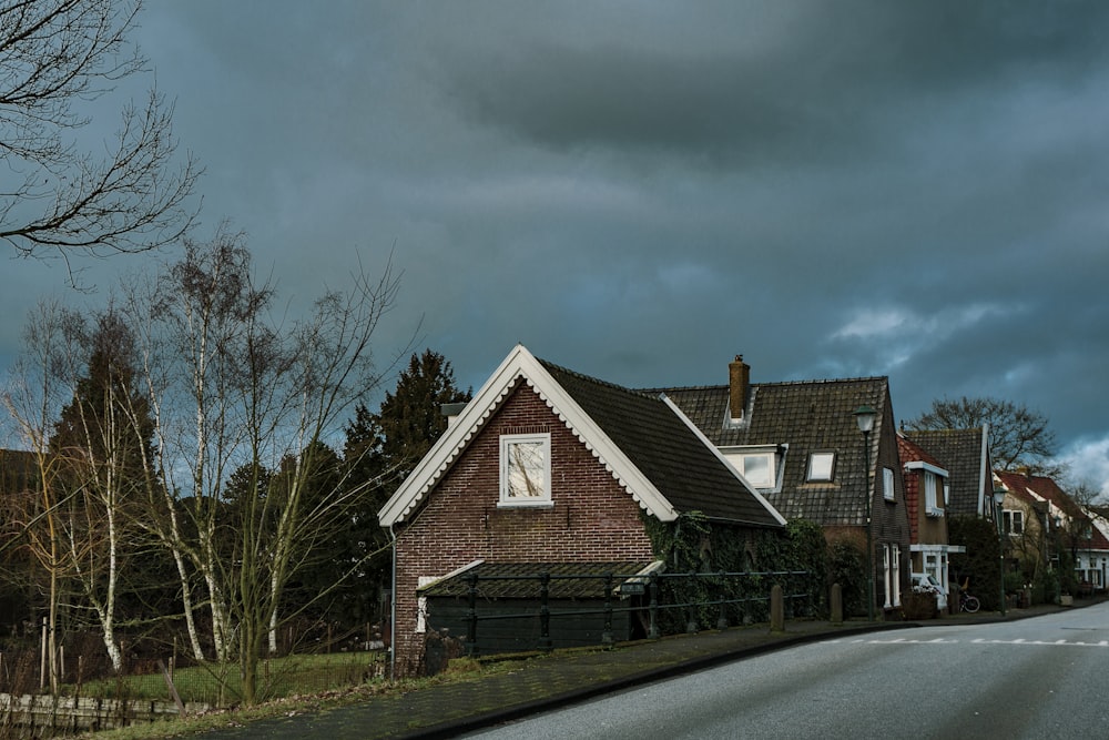 brown and white wooden house near bare trees under gray clouds