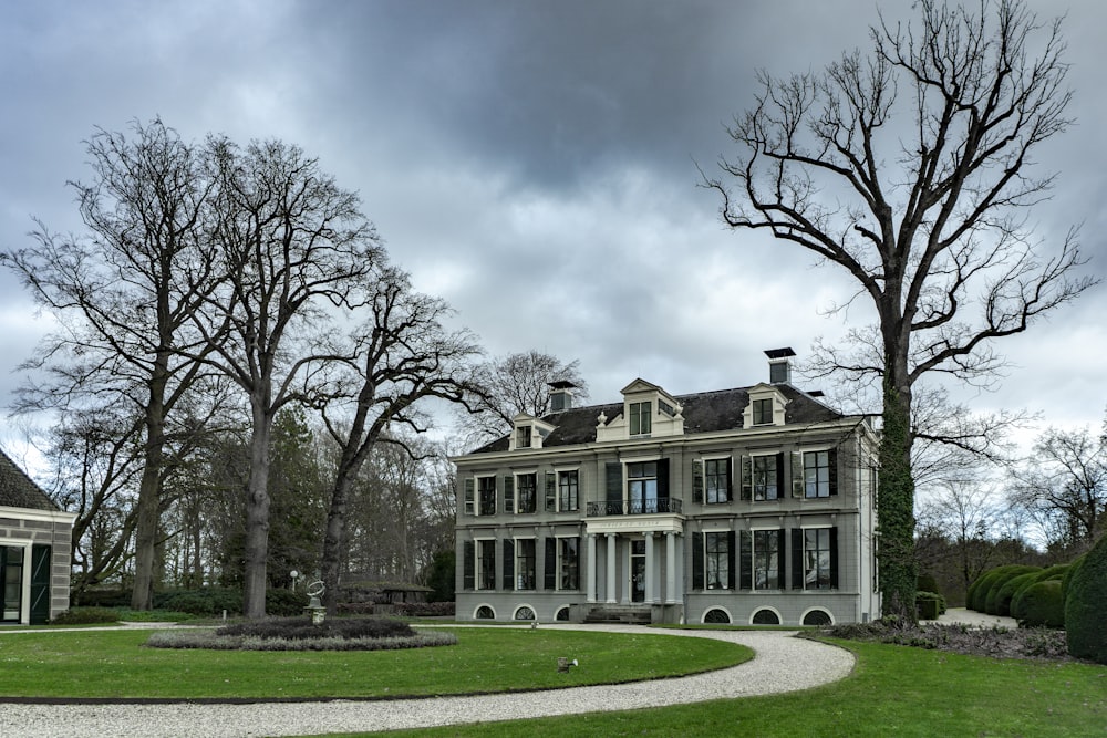 white and black concrete building near bare trees under cloudy sky during daytime