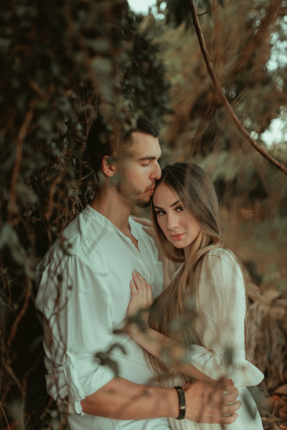 man in white button up shirt kissing woman in white dress