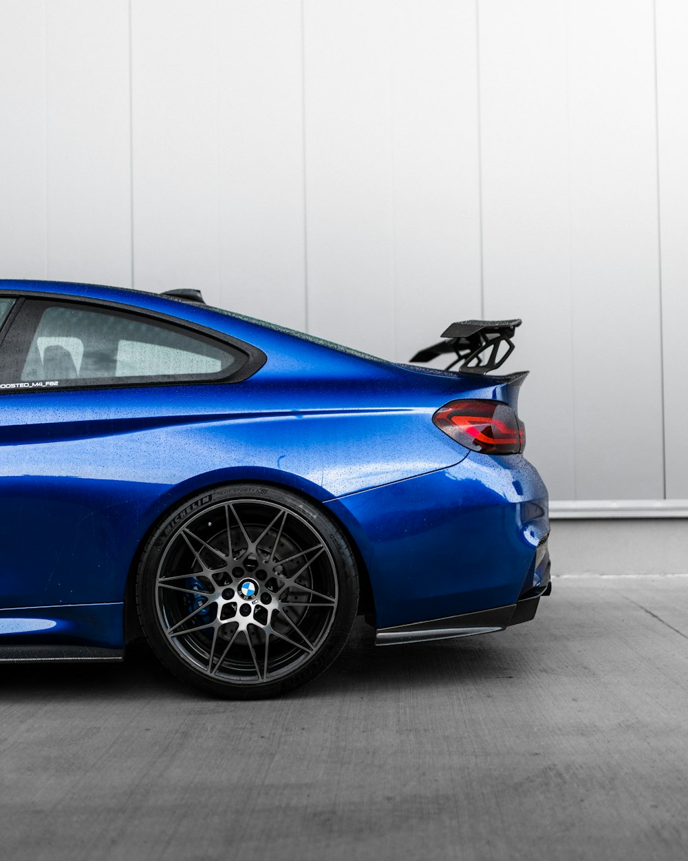 blue car parked in front of white wall