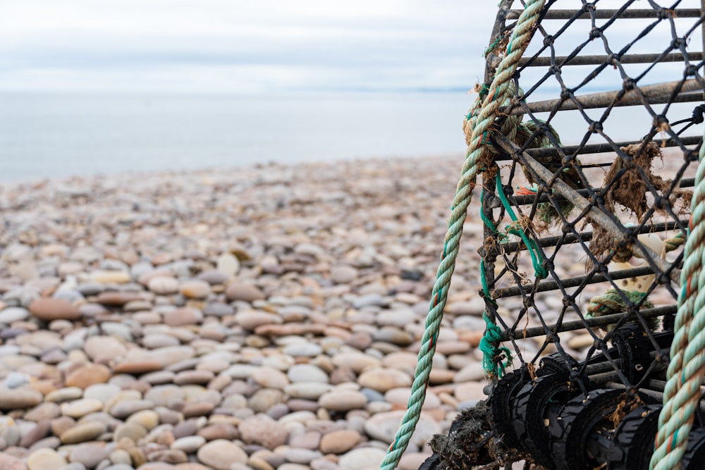 a fishing net on a rocky beach next to the ocean