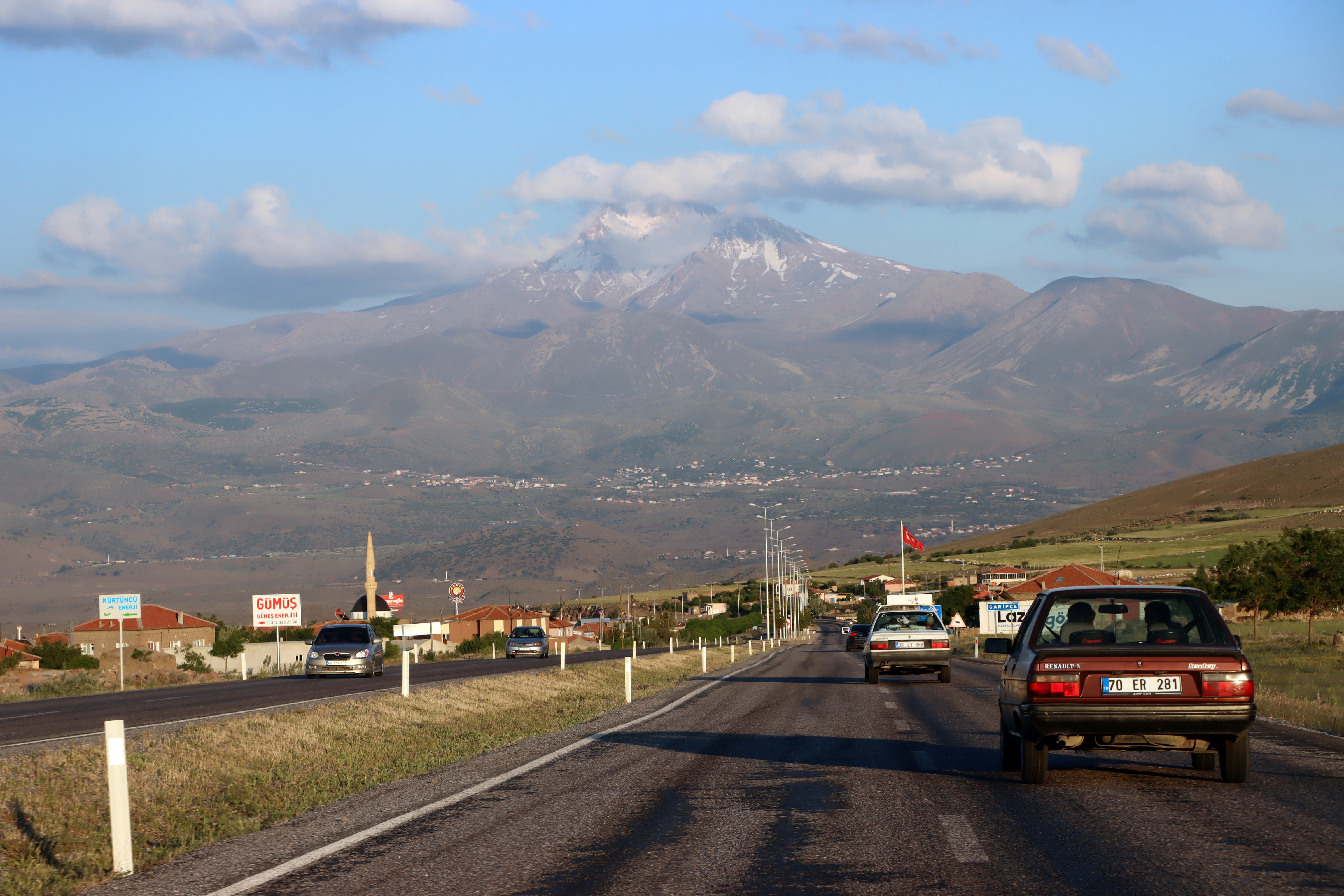 a car driving down a road with a mountain in the background