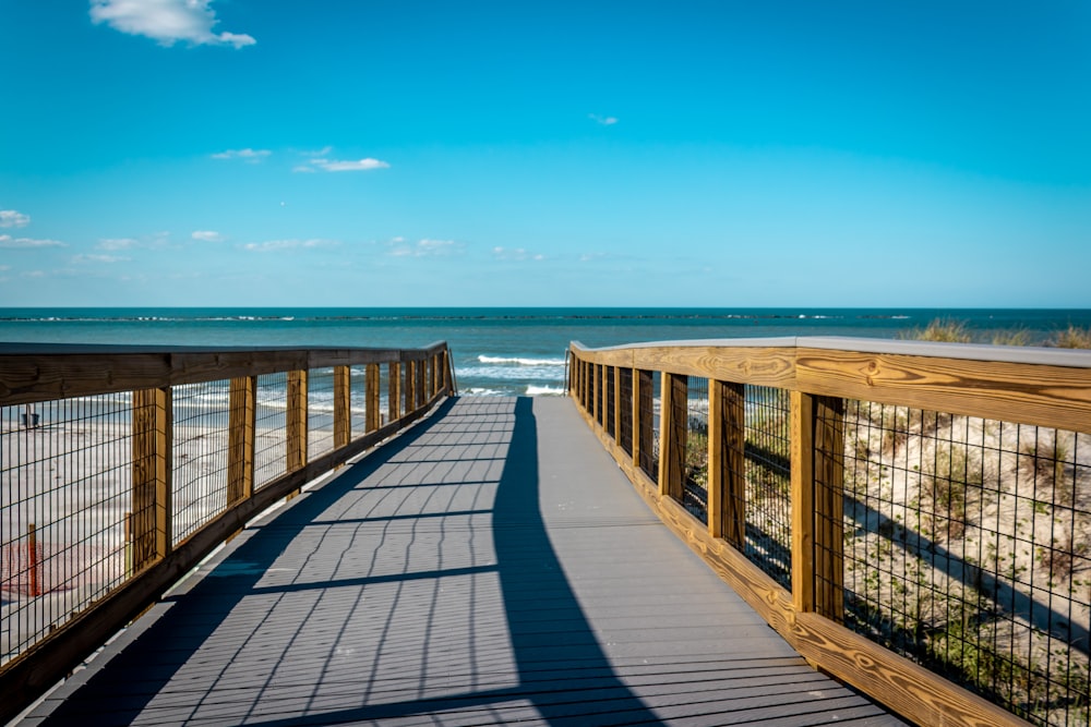 a wooden walkway leading to the beach on a sunny day