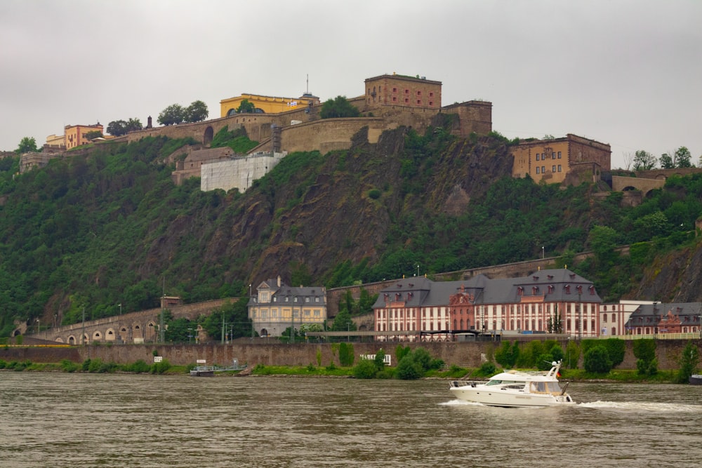 a boat traveling down a river next to a lush green hillside