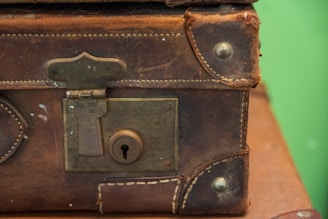brown leather suitcase on white and red textile