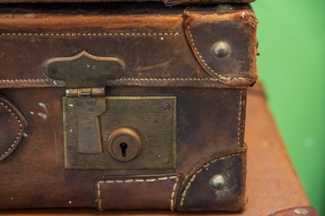 brown leather suitcase on white and red textile