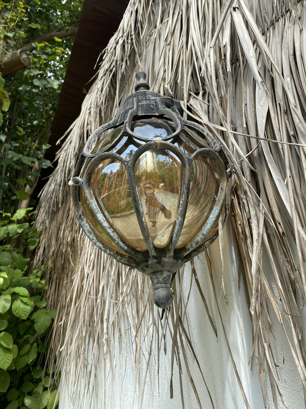 a lamp hanging from the side of a thatched roof