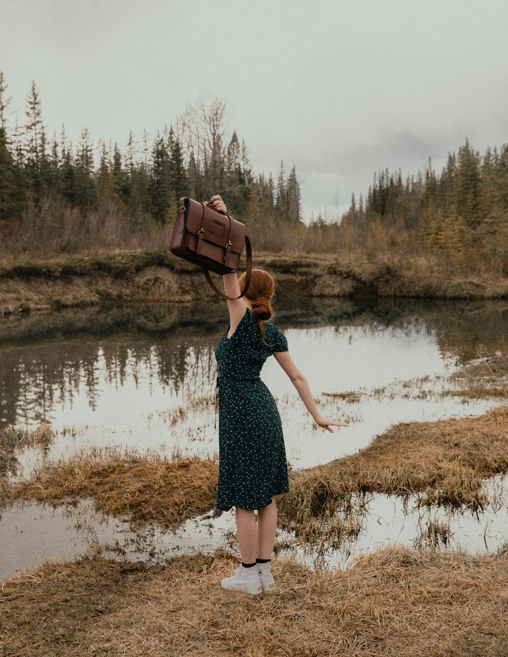 woman in black and white floral dress standing on brown grass field near lake during daytime