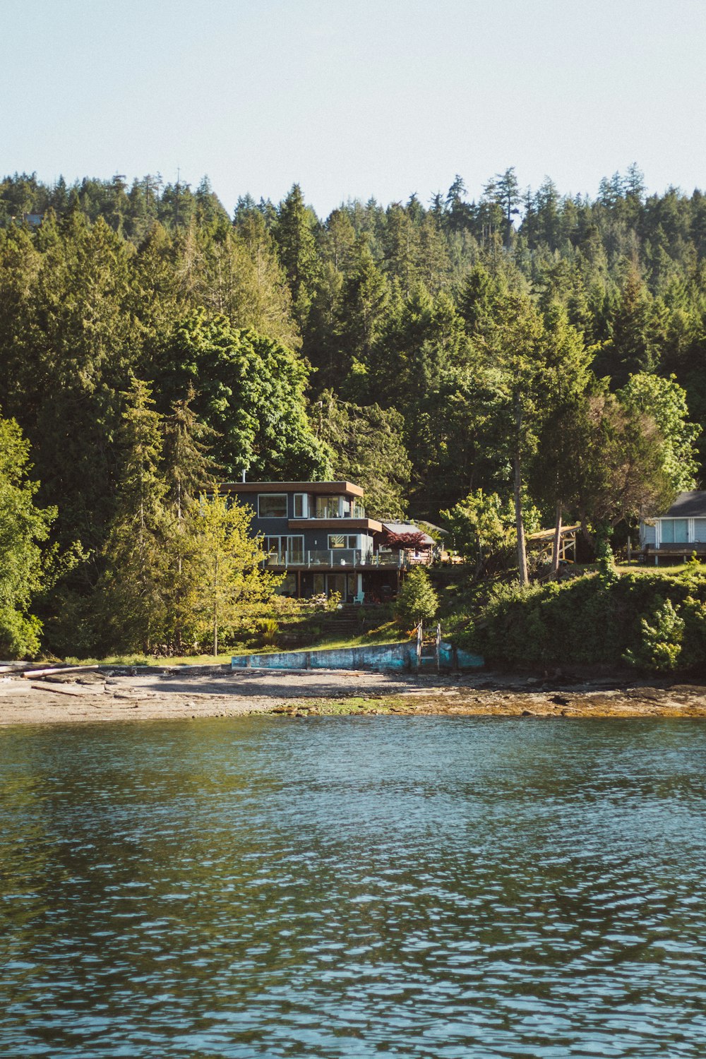 a house on the shore of a lake surrounded by trees