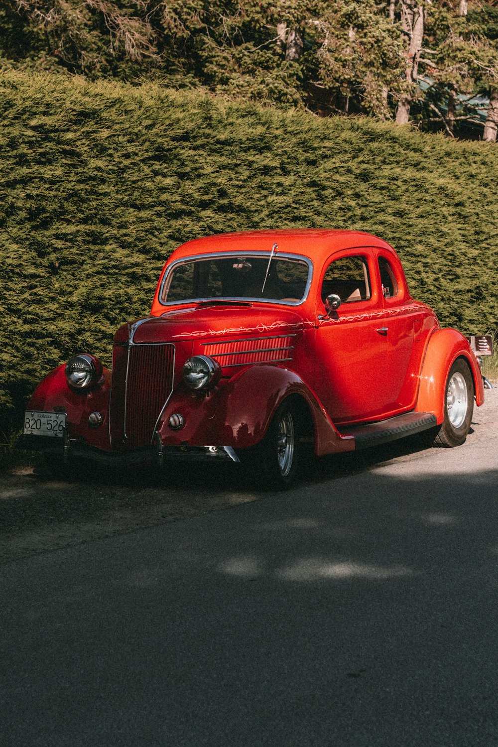 an old red car parked on the side of the road