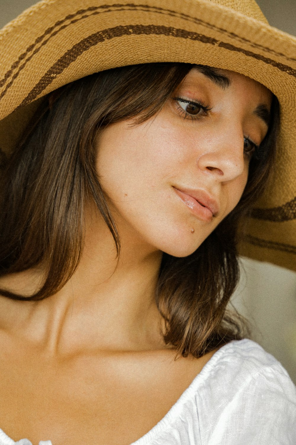 woman in white shirt wearing brown hat