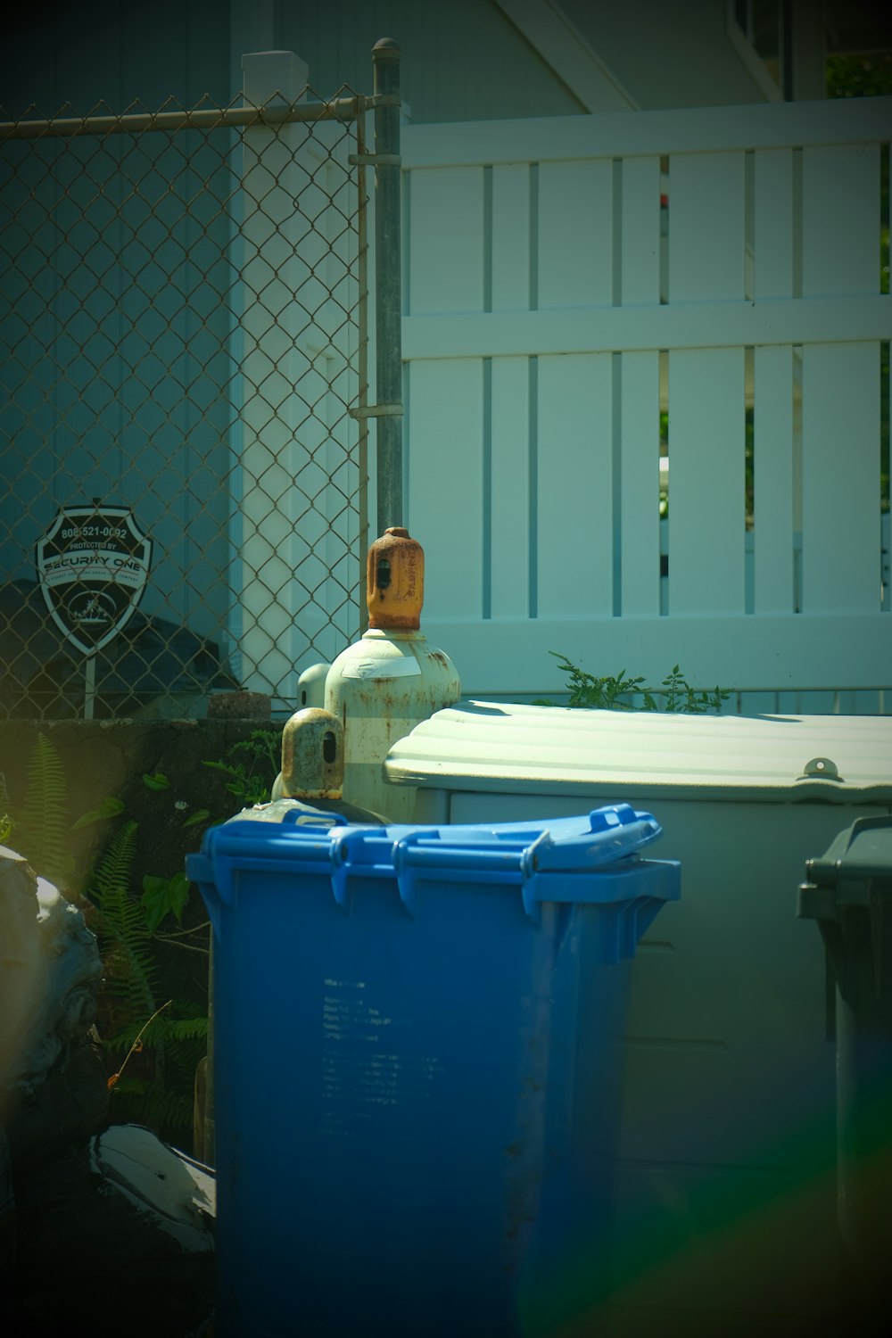 blue plastic trash bin beside white plastic trash bin